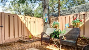 A backyard with a wooden fence, a tree, a bench, and a hanging flower basket. - Community Perks! Sunny Hilton Head Island Retreat (Hilton Head Island)