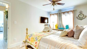 A bedroom with a bed, a ceiling fan, a television, curtains, and a wall clock. - Community Perks! Sunny Hilton Head Island Retreat (Hilton Head Island)