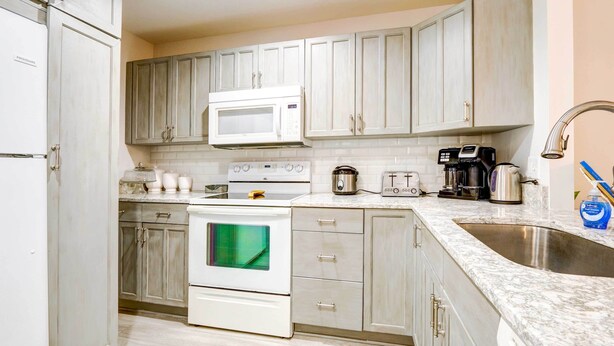 A kitchen with white cabinets, a microwave, stove, oven, and a sink. - Community Perks! Sunny Hilton Head Island Retreat (Hilton Head Island)