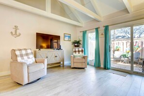 A living room with a sofa, a chair, a cabinet, and a sliding glass door leading to an outdoor area.