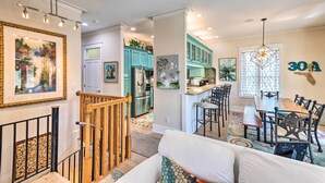 A spacious living area with a wooden staircase, a dining table with chairs, and a kitchen with teal cabinets. - Santa Rosa Beach Home w/ Pool, Hot Tub & Deck! (Santa Rosa Beach)
