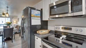 A modern kitchen with stainless steel appliances, a refrigerator with a calendar, a microwave, and an oven. - Grand Junction Vacation Rental: Indoor Pool Access (Grand Junction)