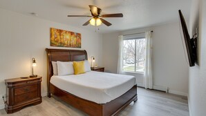 A bedroom with a wooden bed, nightstands, a ceiling fan, and a window with curtains. - Grand Junction Vacation Rental: Indoor Pool Access (Grand Junction)