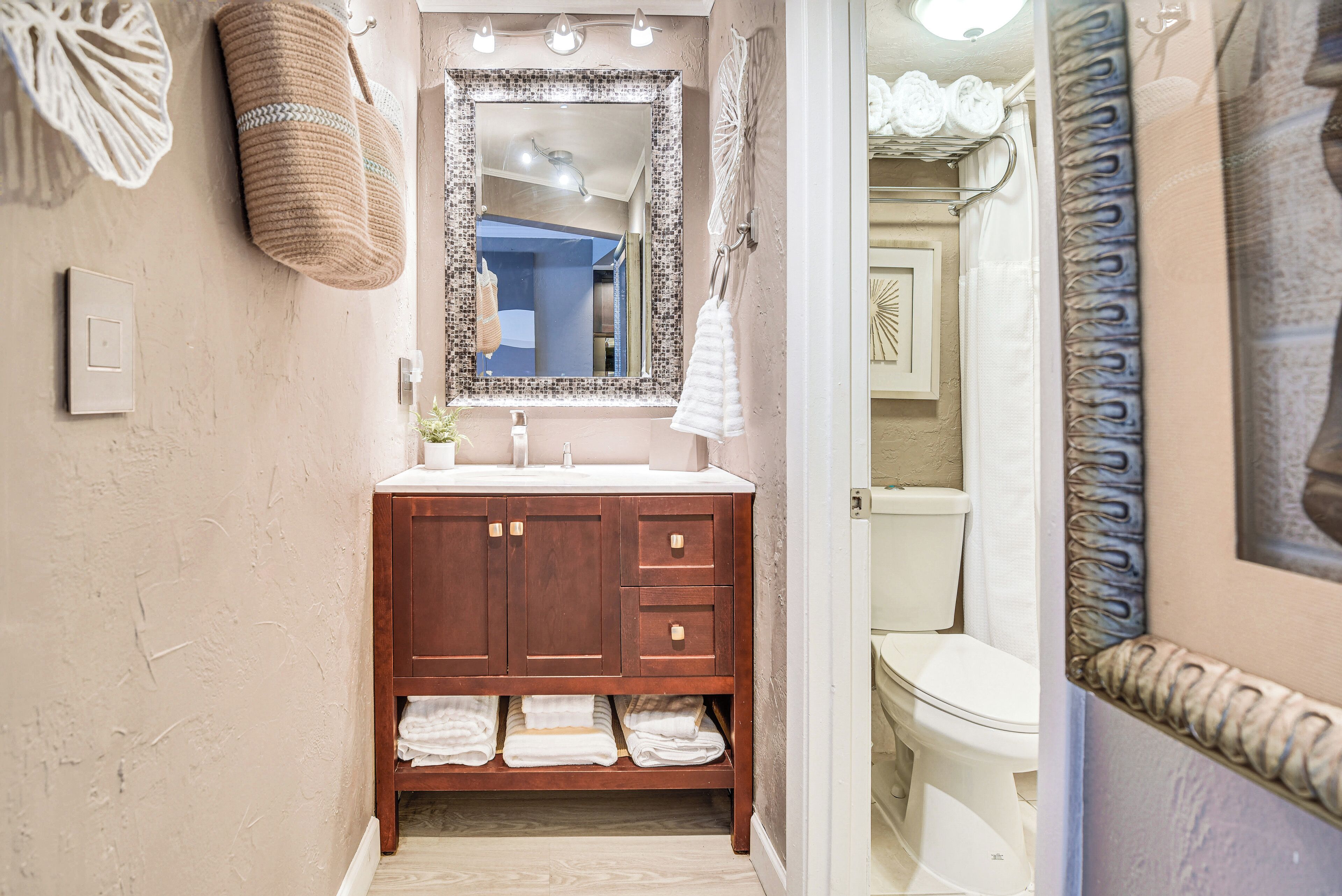 Een badkamer met een houten wastafelmeubel, een grote spiegel en een wit toilet.