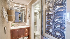 A bathroom with a wooden vanity, a large mirror, and a decorative wall piece. - Daytona Beach Retreat: Beach Access! (Daytona Beach Shores)