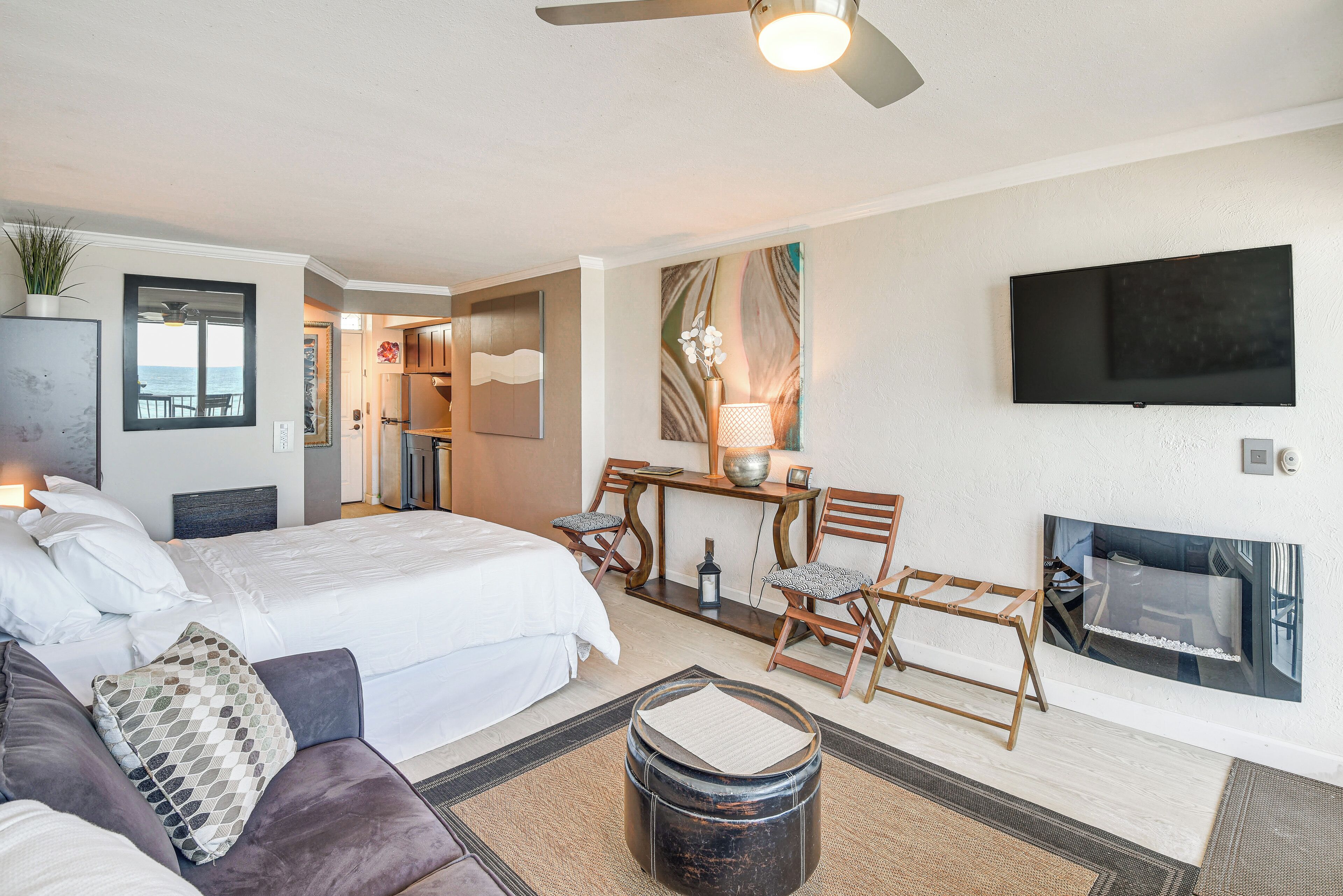 Een hotelkamer met een bed, een slaapbank, een eettafel met stoelen, een aan de muur bevestigde televisie en een open haard.