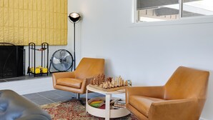 A living room with two brown leather chairs, a wooden coffee table, a chessboard, a fan, and a yellow textured wall. - Borrego Springs Retreat w/ Pool & Mtn Views (Borrego Springs)