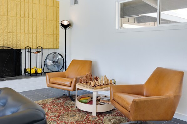 A living room with two brown leather chairs, a wooden coffee table, a chessboard, a fan, and a yellow textured wall. - Borrego Springs Retreat w/ Pool & Mtn Views (Borrego Springs)