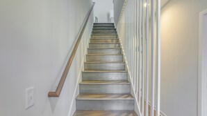 Una escalera de madera con barandilla blanca que lleva a un piso superior.