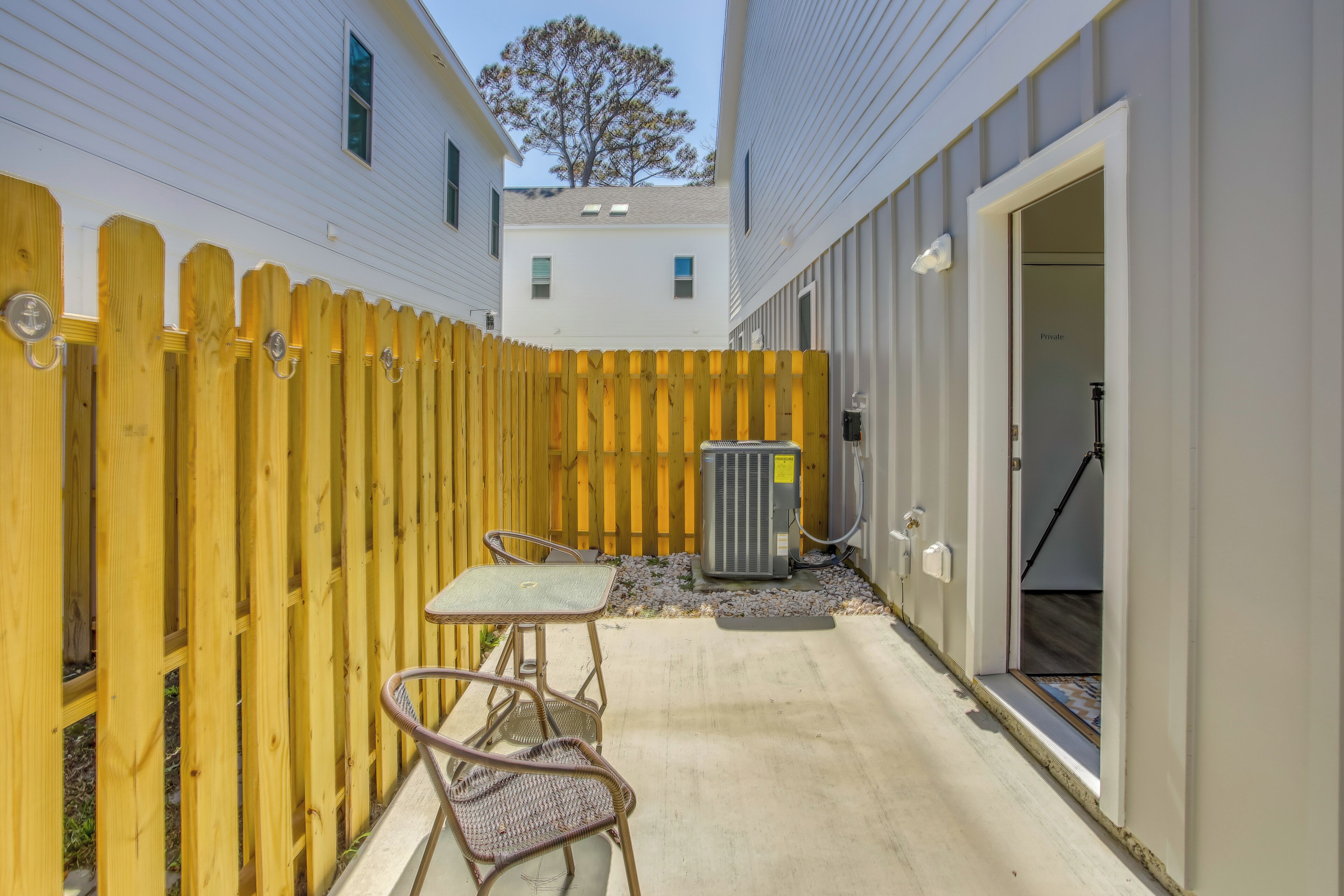 A patio area with a wooden fence, outdoor furniture, and an air conditioning unit.