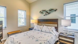Un dormitorio con cama, dos mesitas de noche, un banco y una decoración en la pared.