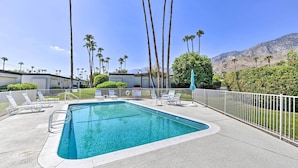 A rectangular pool with a white deck, surrounded by a white fence, palm trees, and a mountain in the background. - Furnished Patio + Pool Access: Palm Springs Condo (Palm Springs)