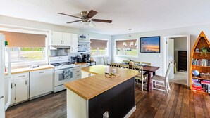A modern kitchen with white cabinets, a wooden island, and a ceiling fan. - Waterfront Deck + Dock: Torch Lake Home! (Rapid City)