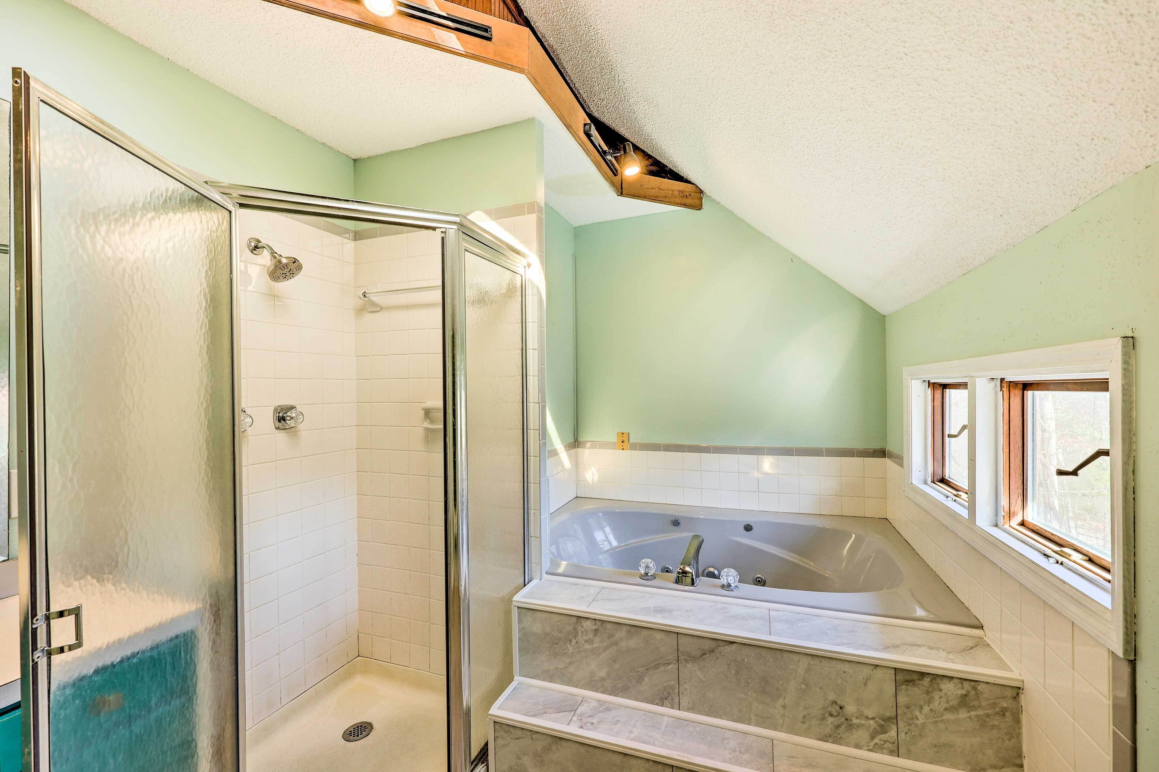 A bathroom with a glass-enclosed shower, a freestanding bathtub, and a window providing natural light.