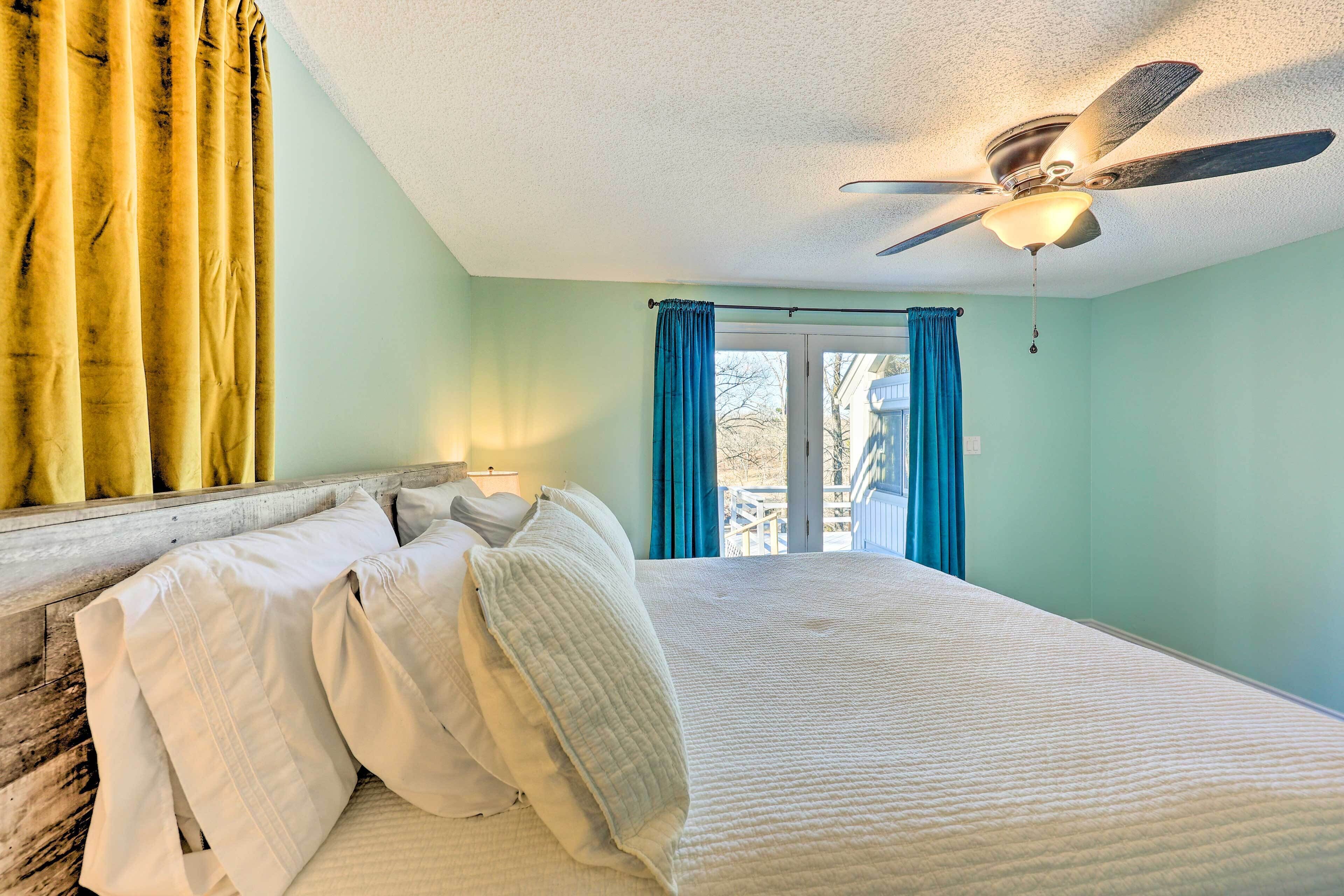 A bedroom with a bed, pillows, a ceiling fan, and curtains.