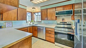 A modern kitchen with wooden cabinets, stainless steel appliances, and a large window. - Near Ouachita River: Home w/ Deck in Hot Springs (Hot Springs)