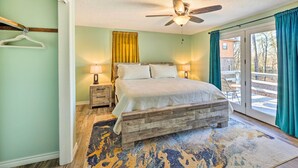 A bedroom with a bed, two bedside tables, a ceiling fan, and a view through a sliding glass door. - Near Ouachita River: Home w/ Deck in Hot Springs (Hot Springs)