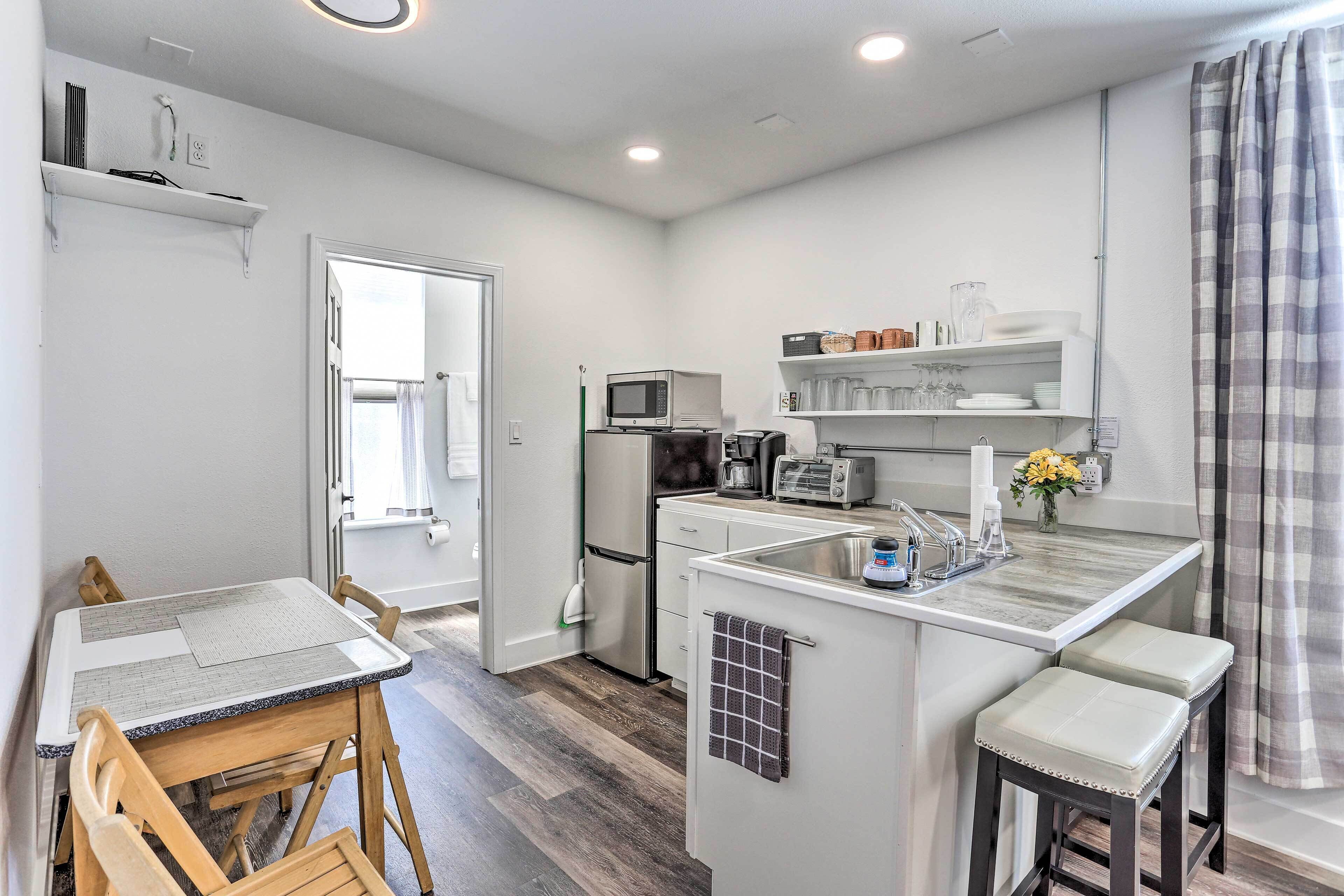 A compact kitchen with a dining area, a microwave, a refrigerator, and a small island with a sink.