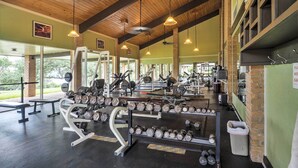 A gym with various exercise equipment, including dumbbells and weight machines, under wooden beams with hanging lights. - Mod Point Venture Townhome w/ Patio + Boat Launch! (Leander)