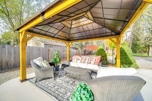 A covered patio area with outdoor furniture, including a sofa and chairs, and a small table with a potted plant. - Lakeview Lodge w/ Spacious Yard: Families Welcome (Nine Mile Falls)