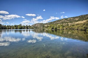 A calm lake with clear water reflecting the sky and surrounding trees. - Lakeview Lodge w/ Spacious Yard: Families Welcome (Nine Mile Falls)