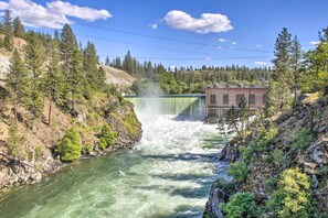 A waterfall cascading into a river surrounded by forested hills. - Lakeview Lodge w/ Spacious Yard: Families Welcome (Nine Mile Falls)