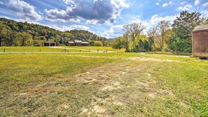 A rural landscape with a fenced field, a wooden building, and a hill with trees. - Dog-friendly Huntsville Home, ATV Authorized Route (Huntsville)
