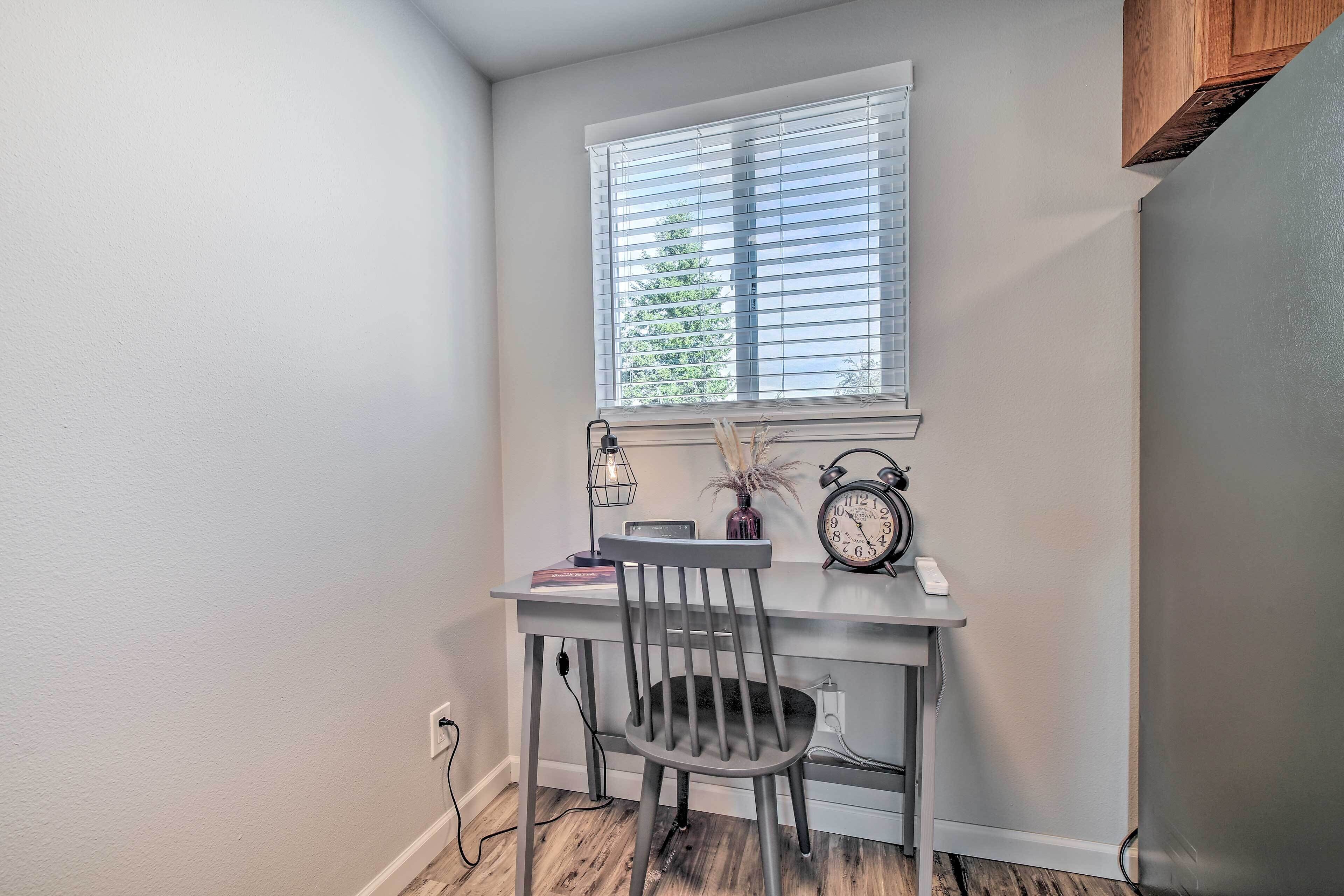 A study area with a desk, chair, window, and a clock.