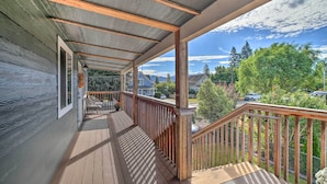 Eine Holzterrasse mit Blick auf ein Wohngebiet, ein überdachter Veranda-Bereich und eine Treppe zu einer oberen Etage.
