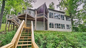 A two-story wooden house with a wooden staircase leading to a deck. - Grand Rapids Area Lakefront House w/ Dock (Lowell)