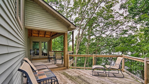A wooden deck with outdoor furniture, a covered patio area, and a view of trees. - Grand Rapids Area Lakefront House w/ Dock (Lowell)