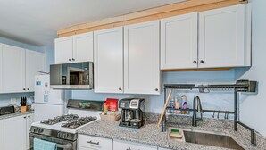 Een moderne keuken met witte kasten, een gasfornuis, een magnetron en een koffiezetapparaat.