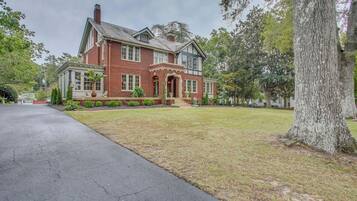 A large, two-story brick house with a well-maintained lawn and a driveway.
