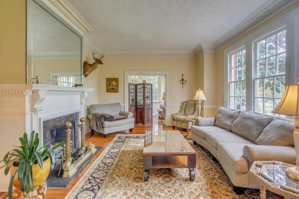 A spacious living room with a fireplace, two sofas, a coffee table, and a large window. - Family Laurinburg Home w/ Private Yard & BBQ (Laurinburg)