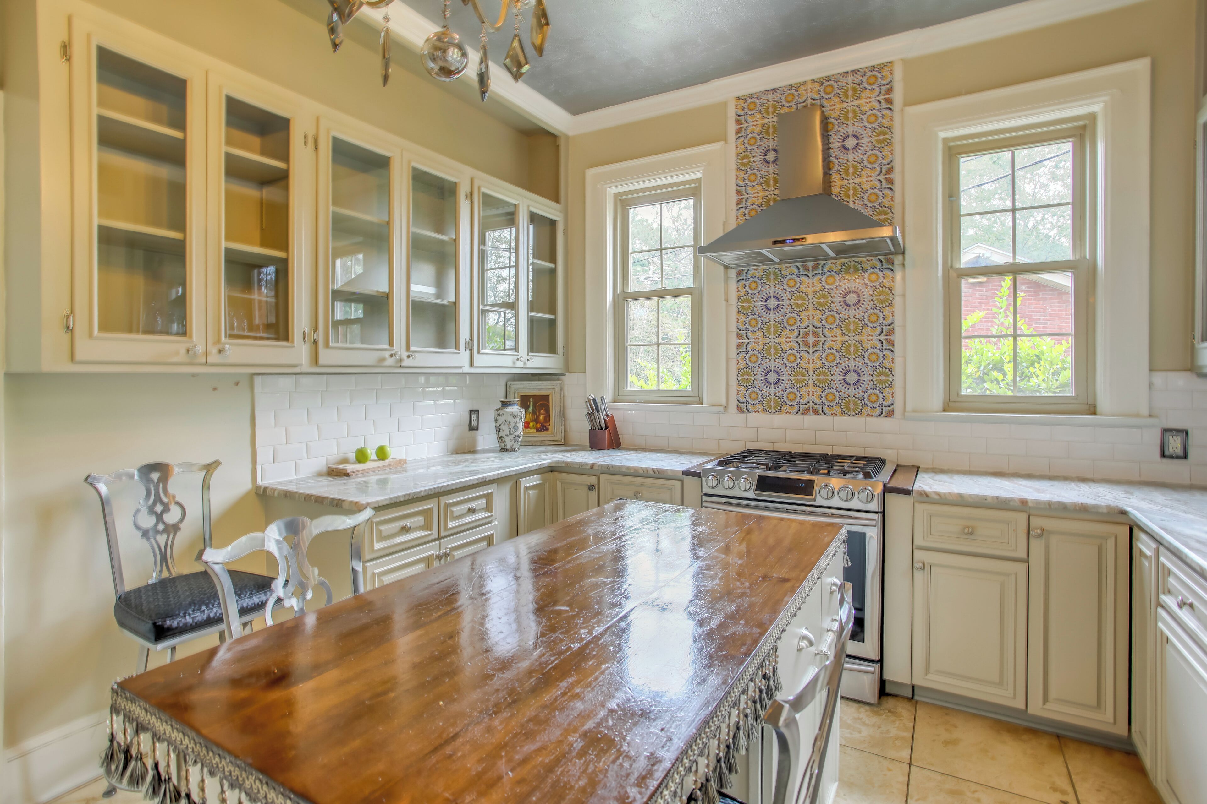 Una cocina con armarios blancos, una isla de madera, una estufa y un salpicadero con diseño.
