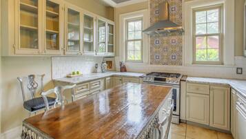 Una cocina con armarios blancos, una isla de madera, una estufa y un salpicadero con diseño.