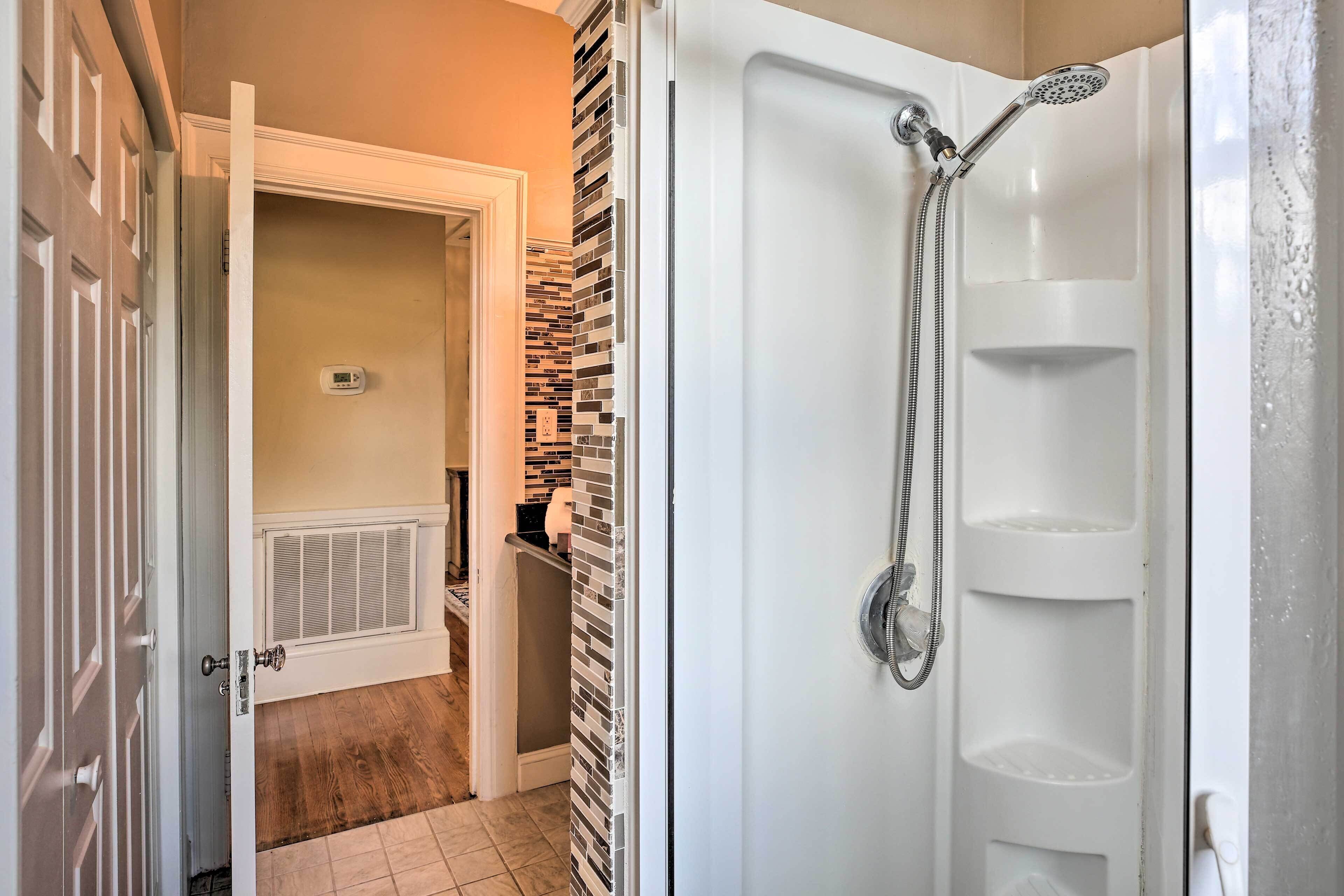 A bathroom with a shower, a toilet, and a radiator.