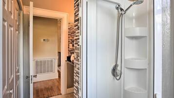 A bathroom with a shower, a toilet, and a radiator.