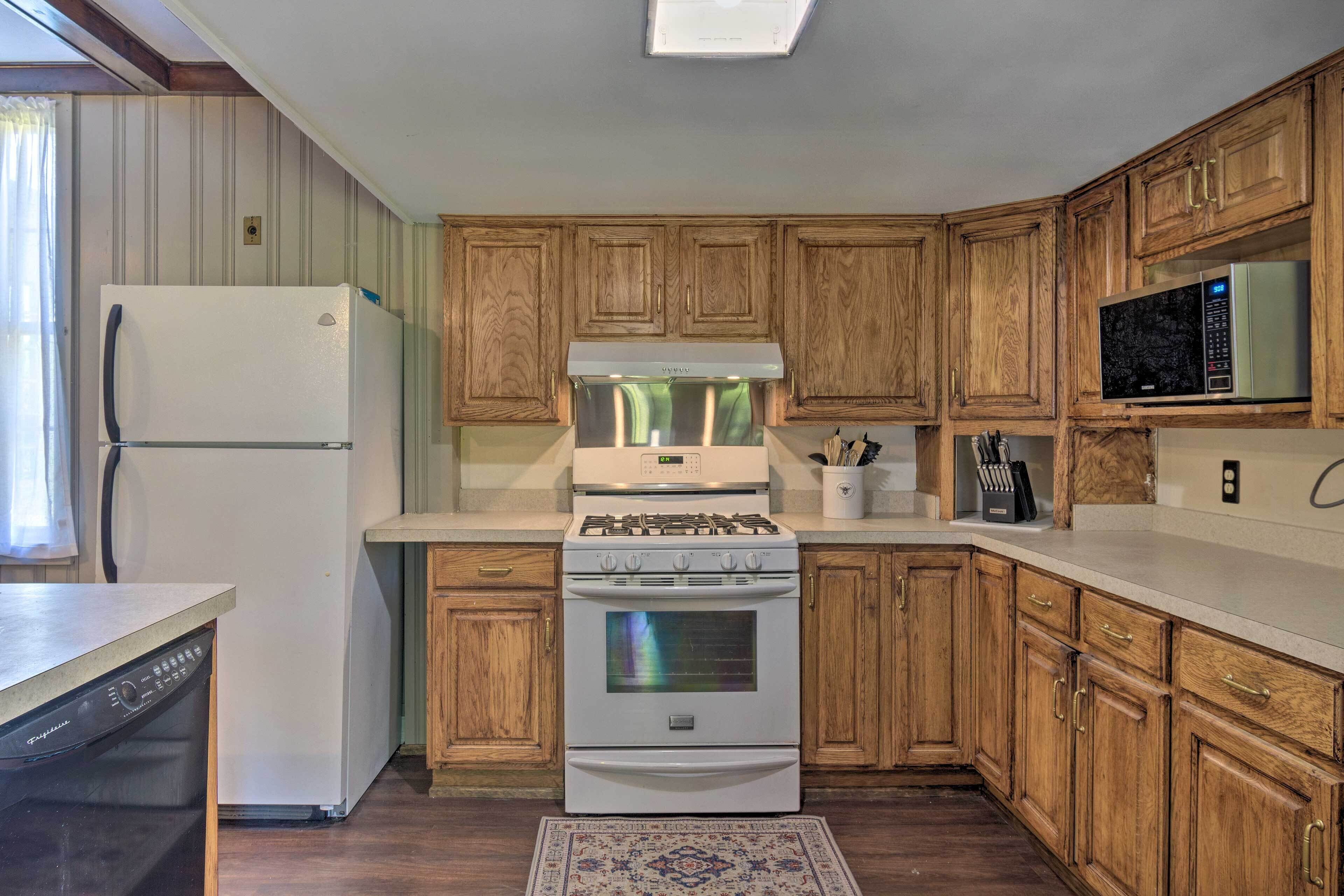 A kitchen with wooden cabinets, a white refrigerator, a stove, and a microwave.