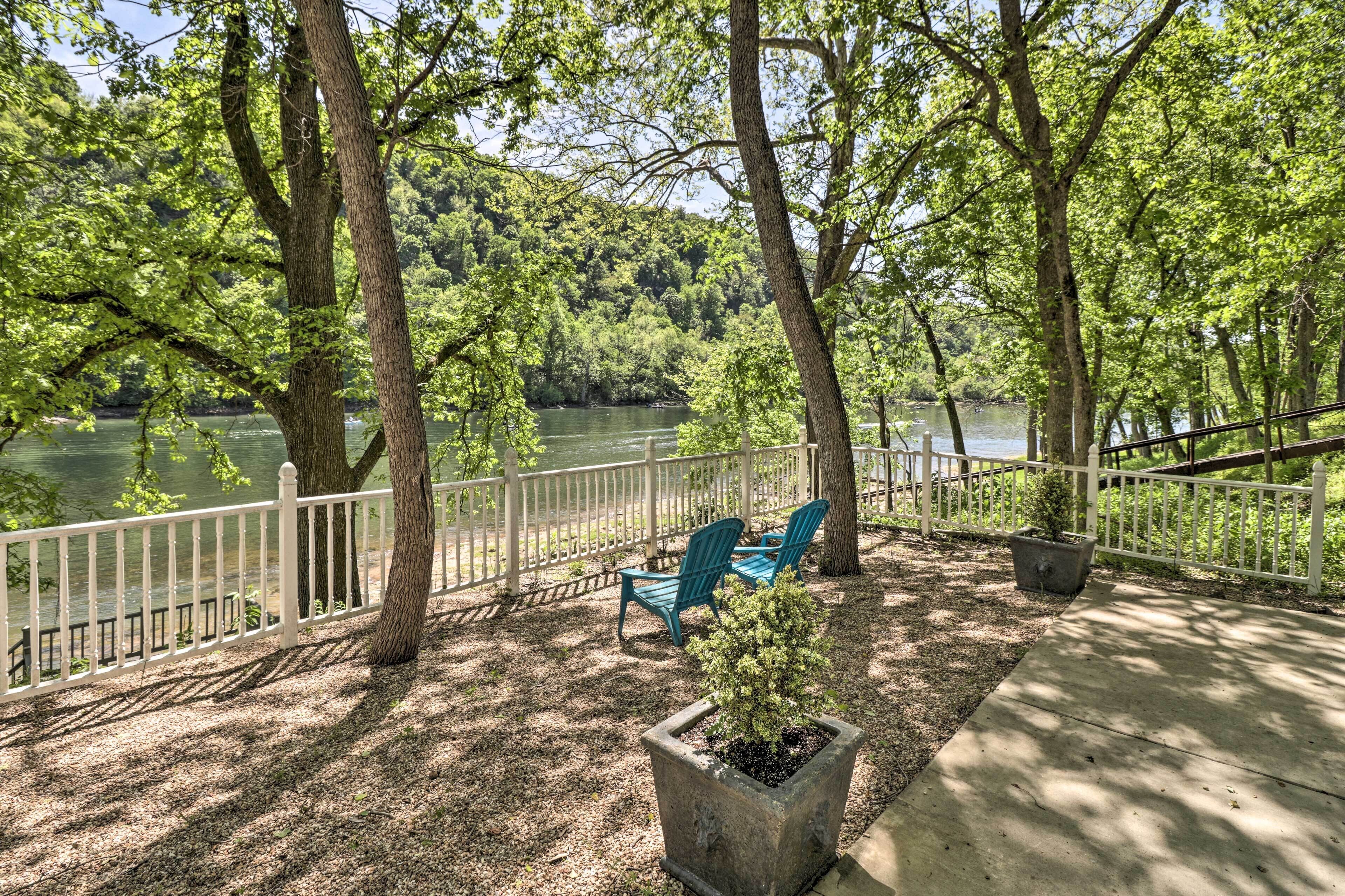 A deck with a white railing, two blue chairs, and a potted plant.