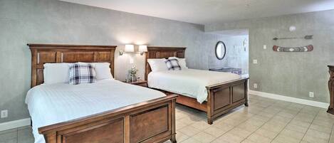 A bedroom with two wooden beds, a round mirror, and a wall-mounted arrow decoration.