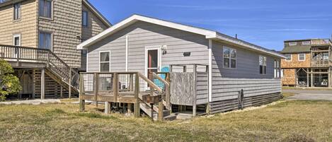 A single-story house with a front deck and a staircase leading to a second-floor balcony.