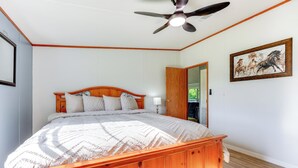 Un dormitorio con una cama de madera, un ventilador de techo y un cuadro enmarcado en la pared.