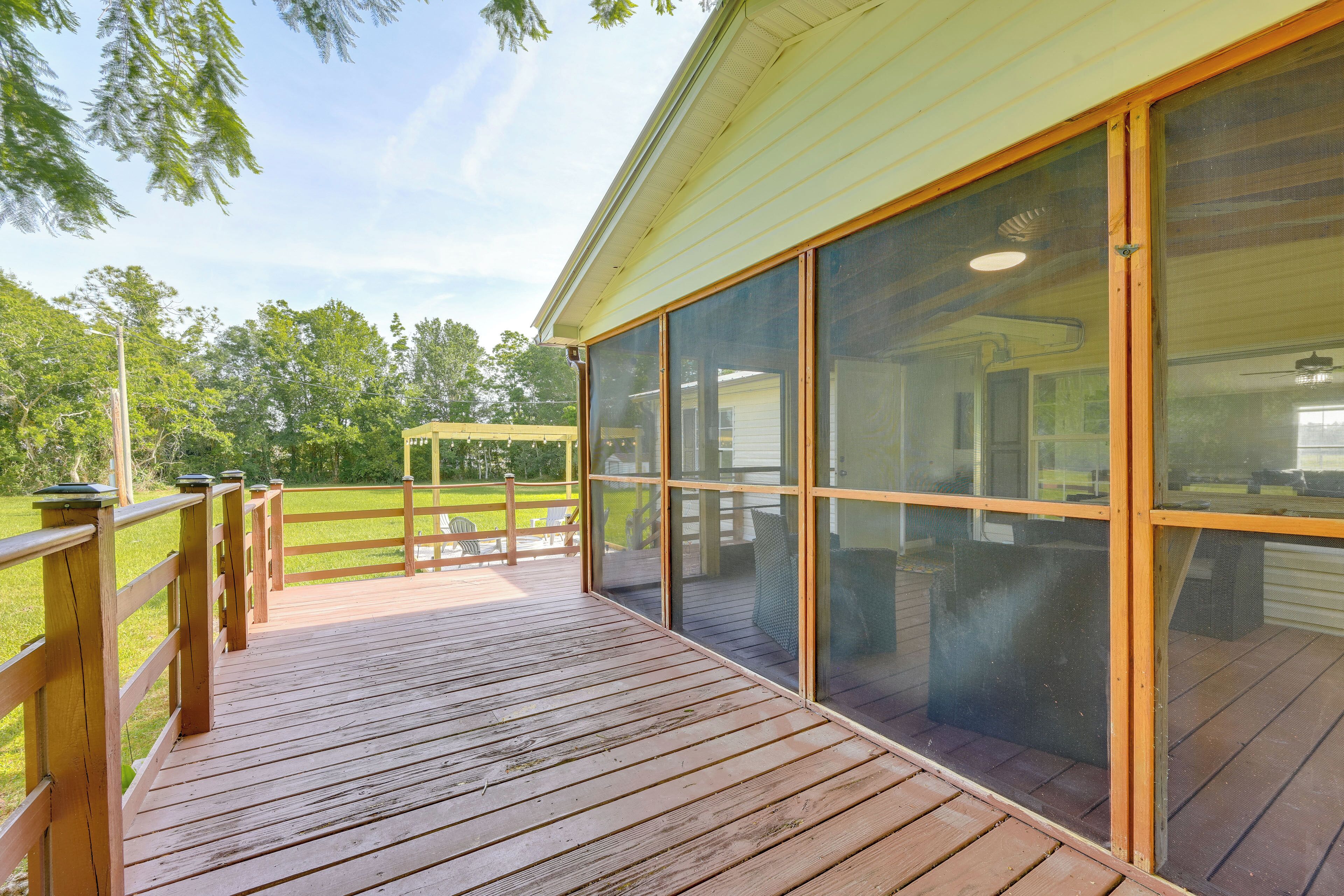 A wooden deck with a covered patio area, large sliding glass doors, and a view of a grassy yard.