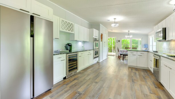 Una cocina amplia con armarios blancos, un refrigerador de acero inoxidable y piso de madera.