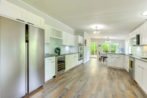 Una cocina amplia con armarios blancos, un refrigerador de acero inoxidable y piso de madera.