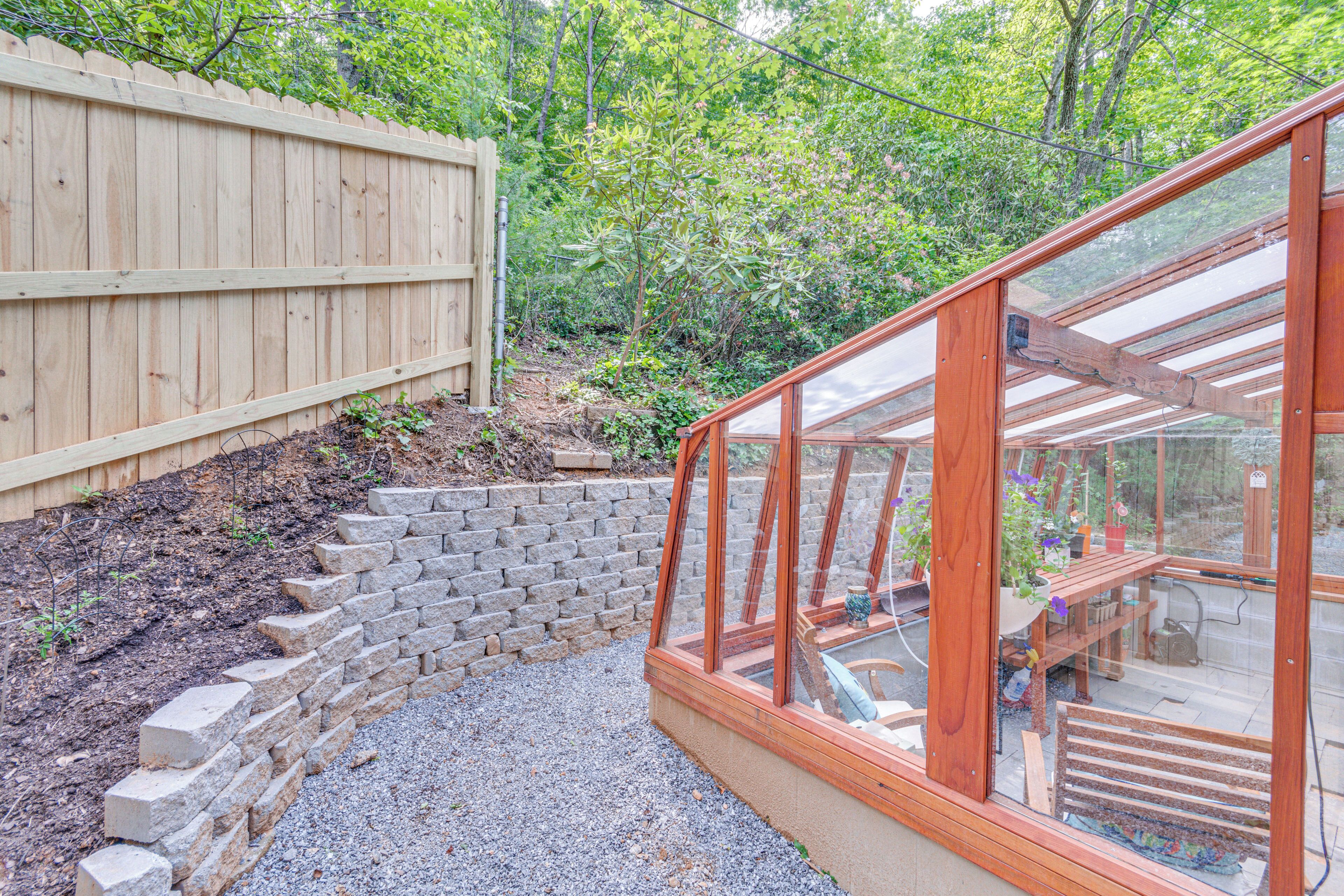 A wooden deck with a glass enclosure, a brick retaining wall, and a wooden fence.