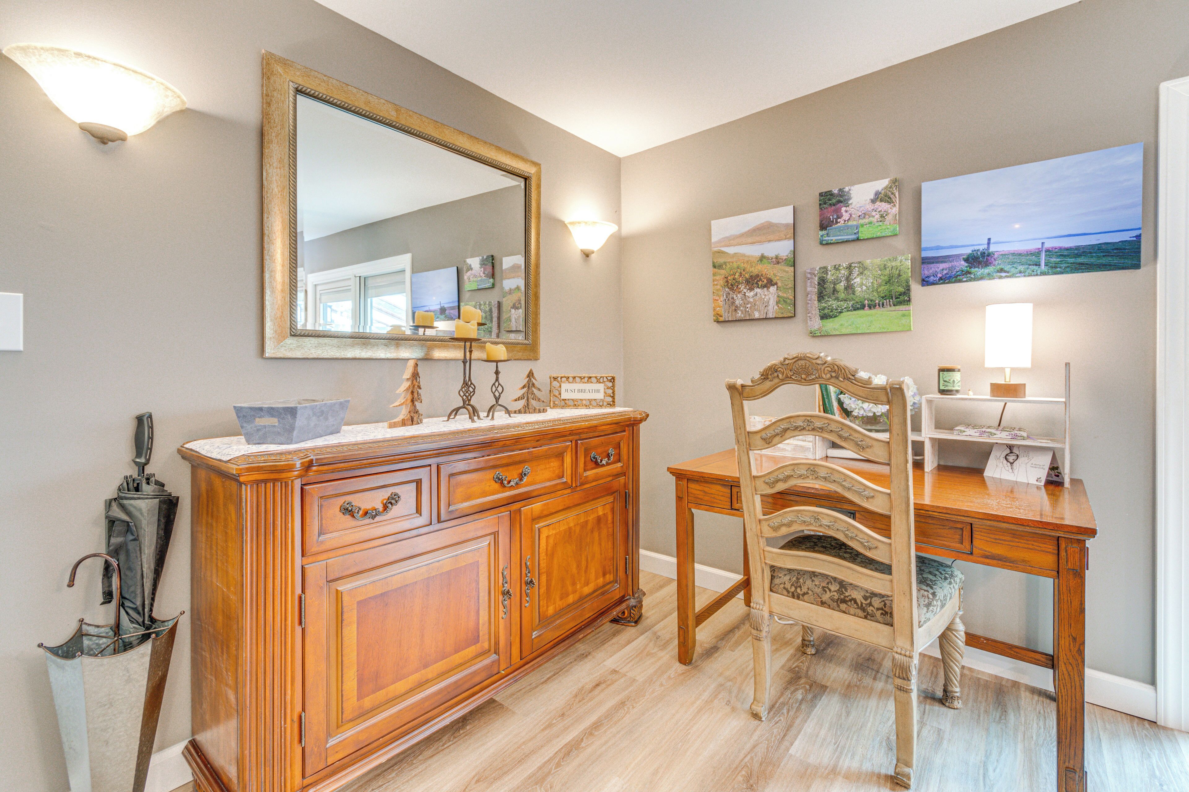 A dining area with a wooden table, chairs, a mirror, and wall-mounted artwork.