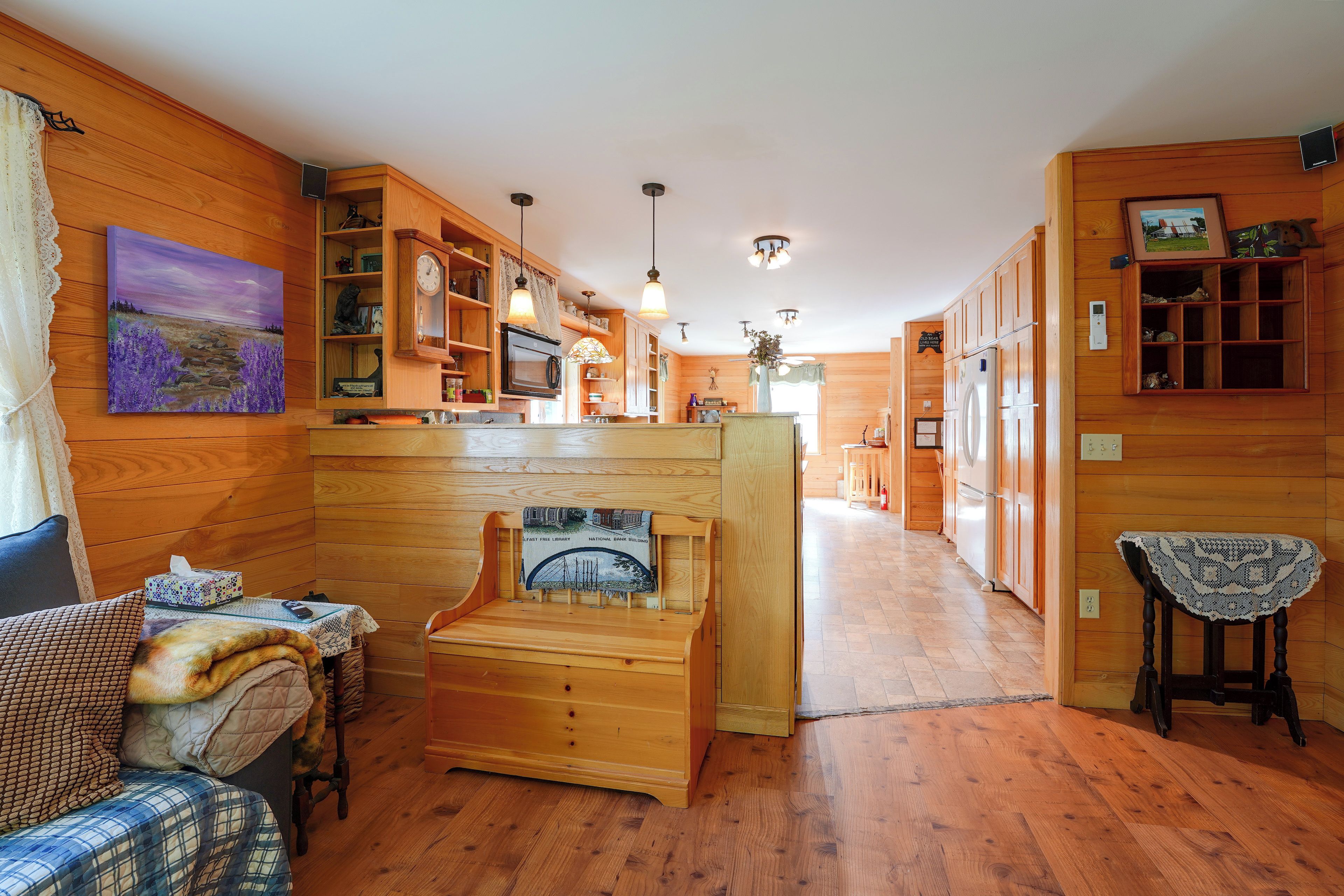 A cozy interior with wooden walls, a fireplace, a dining area, and a kitchen.
