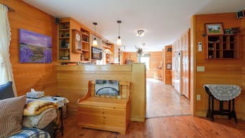 A cozy interior with wooden walls, a fireplace, a dining area, and a kitchen.